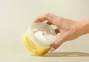 Crema y una mano agarrando el tarro